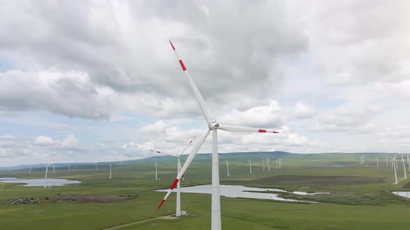 Wind farm with spinning windmill generator located on the windy landscape