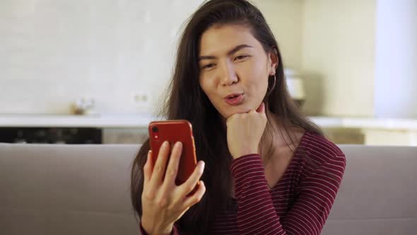 A Happy Young Asian Woman Smiling Reading and Texting on Her Smartphone