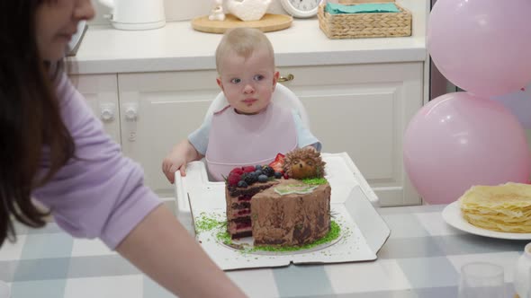 Baby Celebrate First Birthday Holiday Mother Cuts Pieces of Birthday Cake One Year Old Kid Against