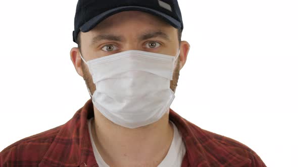 Man in Black Baseball Cap with a Medical Mask on His Face on White Background