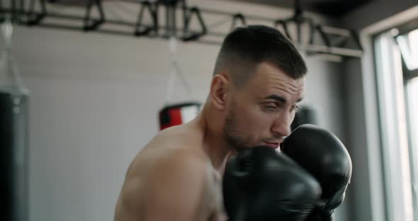 Kickboxer in Boxing Gloves Does Shadow Boxing and Trains at Boxing Club Fighter Man is Fighting with