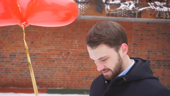 Man with Balloons Waiting for an Outdoor Date