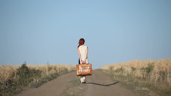 girl with suitcase at countryside road