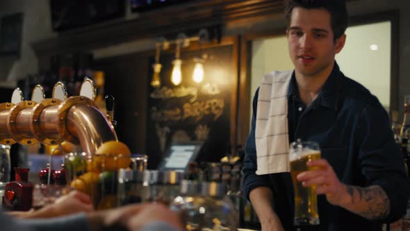 Busy male bartender beer at bar to the clients. Shot with RED helium camera in 8K.