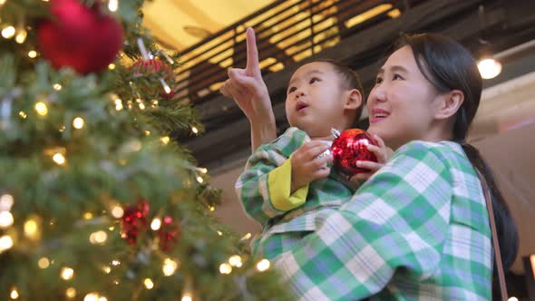 festive celebrating holiday concept asian mom with her son helping put decorating