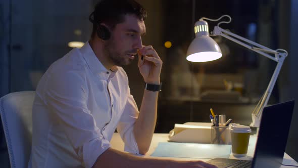 Businessman in Headset with Laptop at Night Office