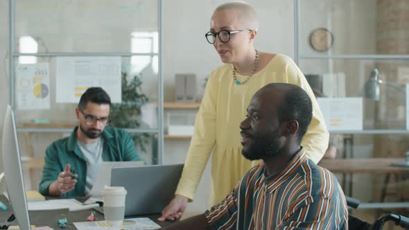 Afro Businessman with Disability Working with Female Colleague in Office