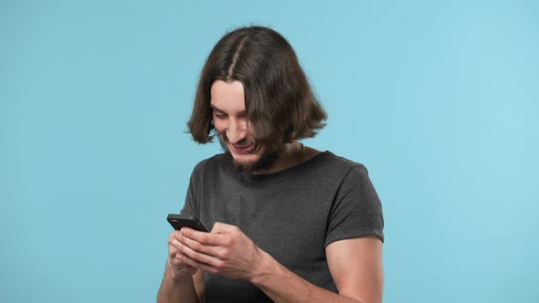 Portrait of Modern Attractive Guy 25s in Casual Chatting or Browsing Internet on Smartphone Isolated