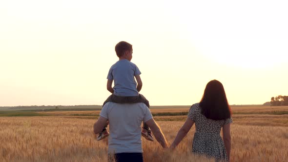 A Family Walk Through a Wheat Field During Sunset