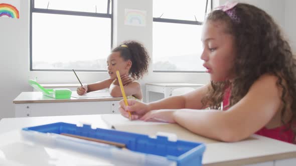 Video of biracial girls sitting at school desks and learning