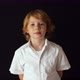 Blonde boy in white shirt stands against black background - VideoHive Item for Sale