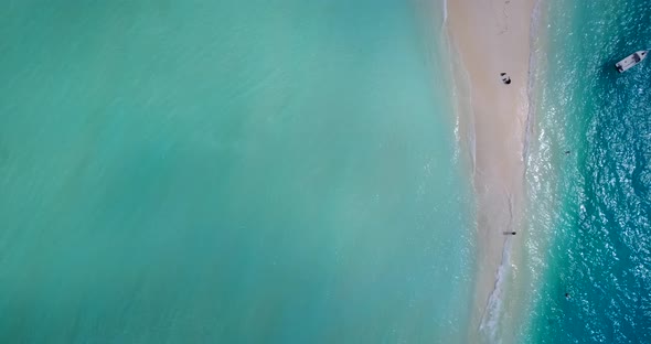 Wide fly over travel shot of a sandy white paradise beach and turquoise sea background in high resol