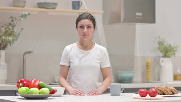 Indian Woman Looking at the Camera While Standing in Kitchen