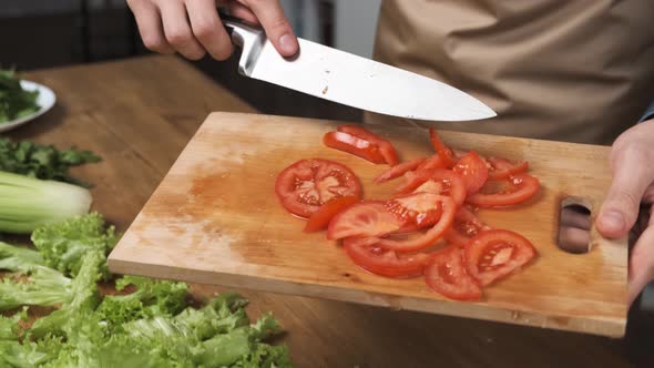 Cooking Salad at Home Man Hands Adding Chopped Red Tomato Slices To Glass Salad Bowl