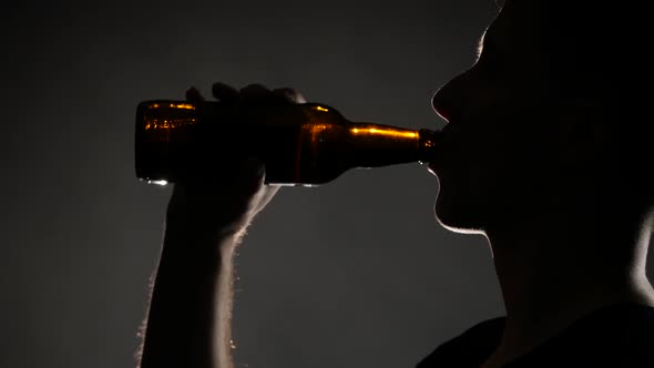 Man Drinking Beer From a Bottle. Grey. Close Up