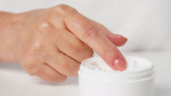 Female Hand Taking Moisturizing Cream for Face or Body on White Background