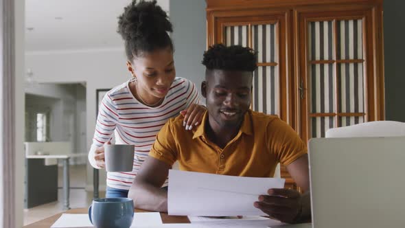 Video of happy african american couple using laptop, paying bills