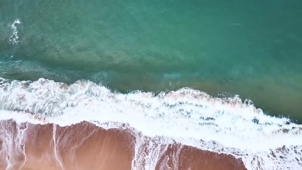 Aerial Top View of Ocean Waves Reaching Beach Shore. Drone Footage.