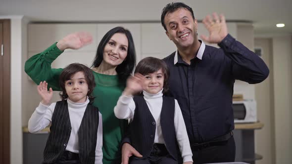 Happy Cheerful Multiethnic Family Waving Smiling Looking at Camera Indoors
