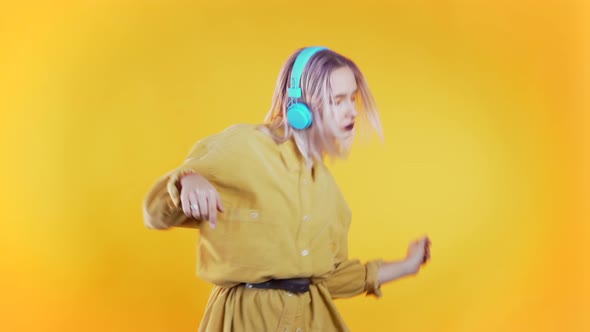 Beautiful Woman with Pink Hair Dancing with Headphones on Yellow 