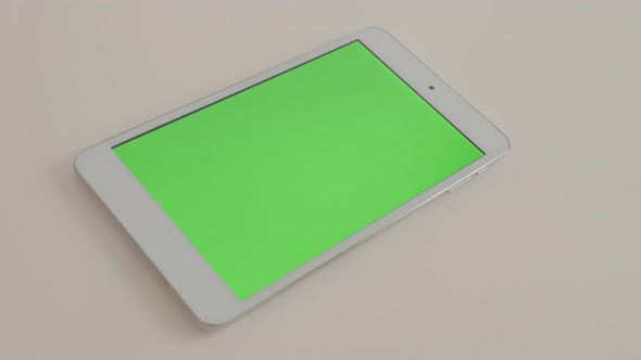 Silver tablet computer on white reflective background displaying chroma  green screen  4K 2160p Ultr