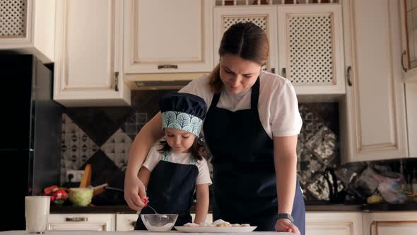 Close-up of Mother with a Little Daughter Sprinkled with Powdered Sugar Cookies.