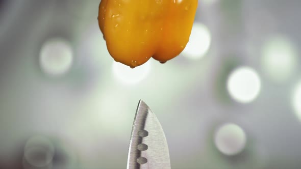 Fresh Yellow Bell Pepper Falling Down with Water Drops on Knife Stuck