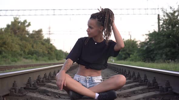 Young Sexy Woman is Sitting on the Rails on the Railroad