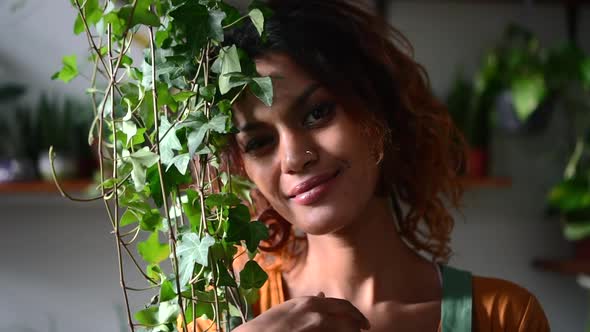 Woman Gardener Poses with Green Plant and Smiles at Light Home Interior Spbd