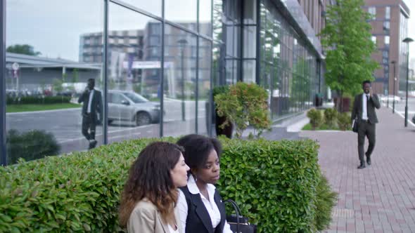 Businesswomen Chatting On Bench Outdoors