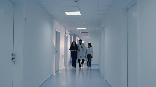 Three Doctors Quickly Walk Down the Corridor of the Hospital to Catch Up with the Patient