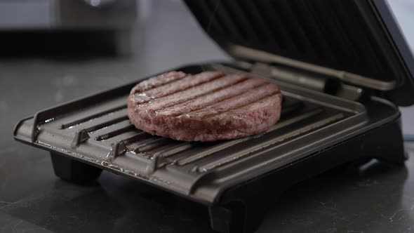 A man cooks a delicious hamburger on a small electric grill
