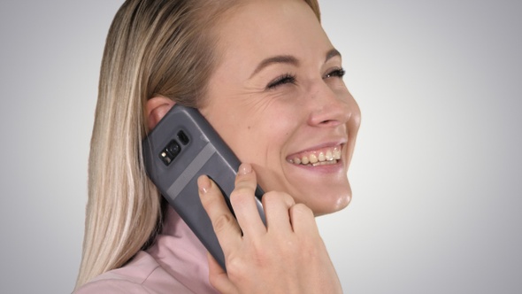 Smiling blonde talking on the phone on gradient background.