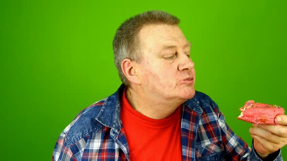 Senior Adult Caucasian Ethnicity Man Savoring with Pleasure Eats Cake with Cream Filling