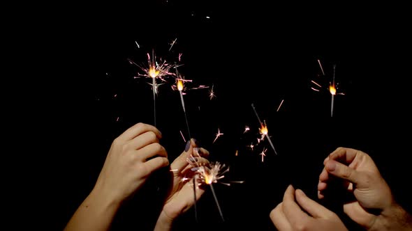 Hands holding and waving Bengal fires New year sparkler candle burning on a black background