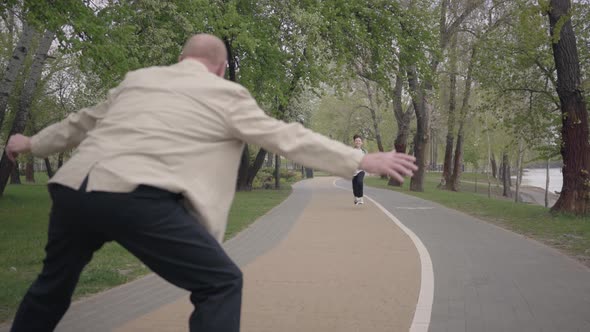 Bald Grandfather Standing in the Foreground Putting Hands Apart for Hugs