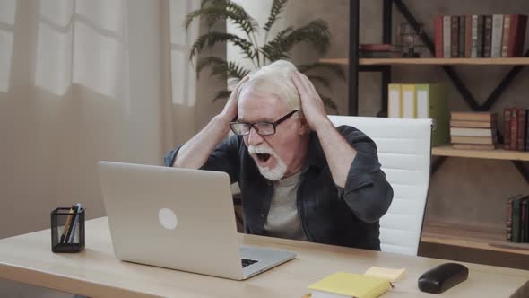 Shocked Stressed Senior Mature Man Looking at Laptop Reading Unbelievable Online News at Home, Crazy