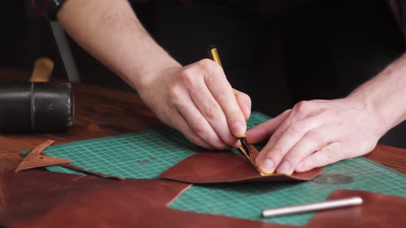 Man Tailor Cutting Artificial Leather with Ruler Closeup