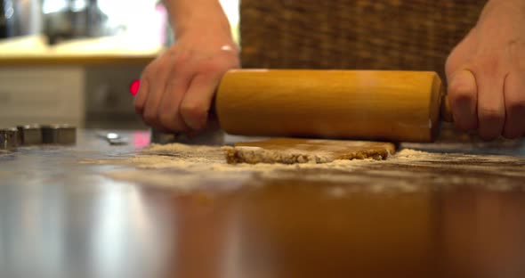 Young male preparing gingerbread cookies for Christmas. Flattening dough with rolling pin