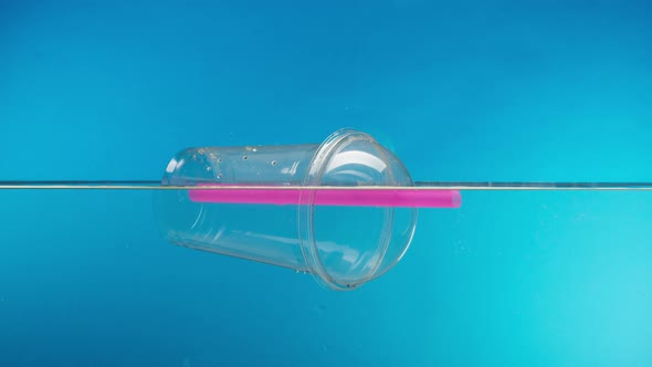 Floating Plastic Glass with a Cocktail Tube in the Ocean Throwing Garbage Into the River or Lake