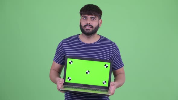 Happy Young Overweight Bearded Indian Man Talking While Showing Laptop