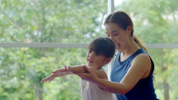 Young mother teaching her cute daughter for exercise