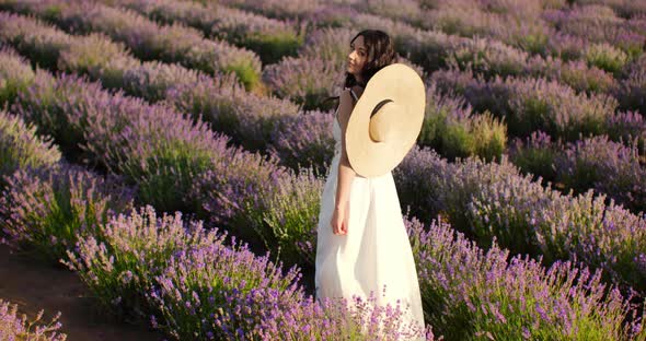 a Girl in a White Dress Walks Through a Lavender Field