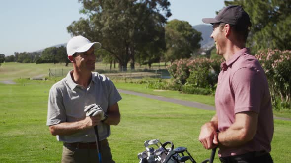 Caucasian male golfers talking on a golf course on a sunny day