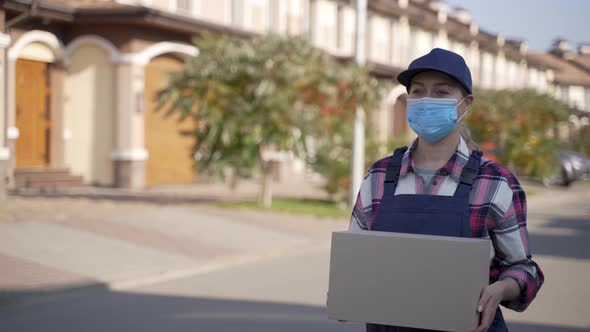 Masked Female Courier Carrying Cardboard Box