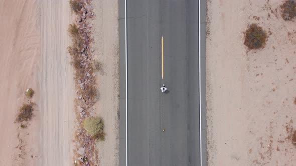 A man walking on a highway in the desert.