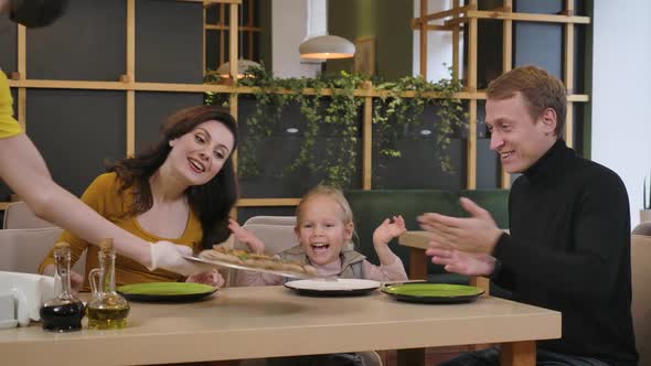 Happy Positive Man Woman and Girl Rejoicing Pizza in Restaurant