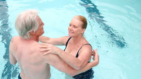 Happy senior couple dancing in pool