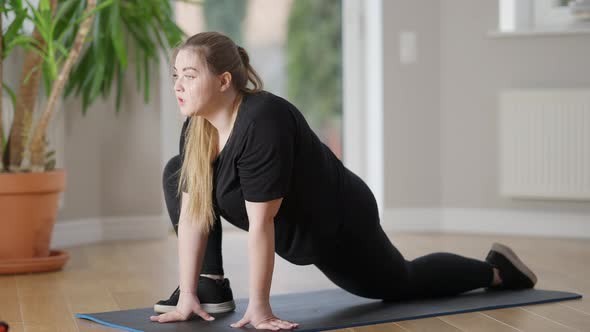 Concentrated Persistent Plump Sportswoman Stretching Leg Muscles in Twine Pose on Exercise Mat