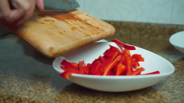 a woman's hand adds red paprika to a plate on a wooden board